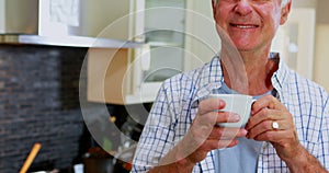 Happy senior man having coffee in kitchen 4k