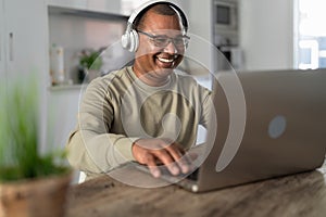 Happy senior man having fun doing video call using laptop at home