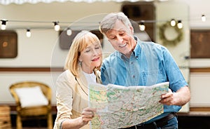 Happy senior man and his wife reading map together at campsite, empty space