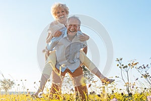 Happy senior man laughing while carrying his partner on his back photo