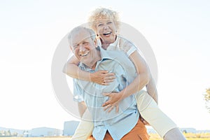 Happy senior man laughing while carrying his partner on his back