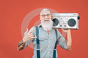 Happy senior man listening to music with boombox outdoor - Crazy hipster male having fun dancing with vintage stereo