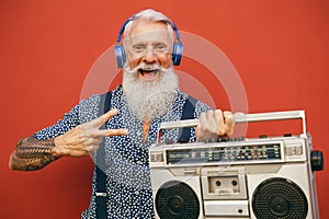 Happy senior man listening to music with wireless headphones and vintage boombox