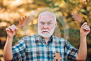 Happy senior man looking at camera. Senior man walking in the park in autumn. Senior man strolling in a park in autumn