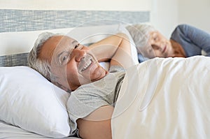 Happy senior man lying on bed