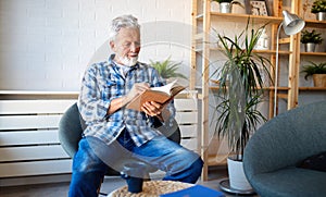 Happy senior man reading book at home