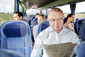 Happy senior man reading newspaper in travel bus