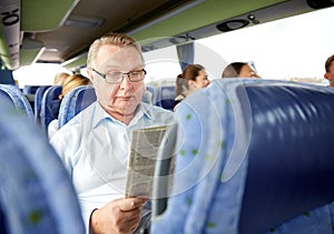 Happy senior man reading newspaper in travel bus