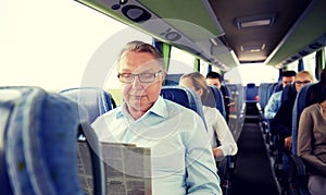 Happy senior man reading newspaper in travel bus
