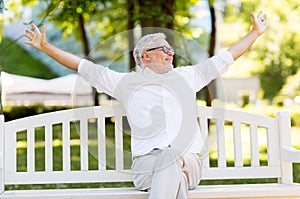 Happy senior man sitting on bench at summer park