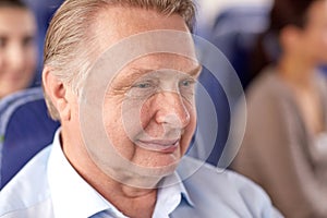 Happy senior man sitting in travel bus or airplane