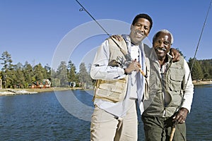 Happy Senior Man And Son With Fishing Rods By Lake