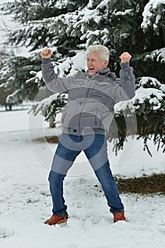 Happy senior man standing outdoors in winter