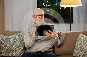 Happy senior man with tablet computer at home