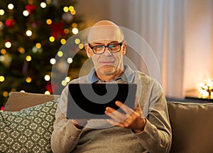 happy senior man with tablet computer at home