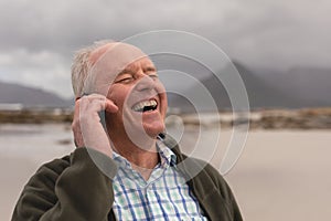 Happy senior man talking on mobile phone at beach