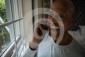 Happy senior man talking on mobile phone by window