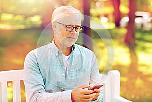 Happy senior man texting on smartphone at summer