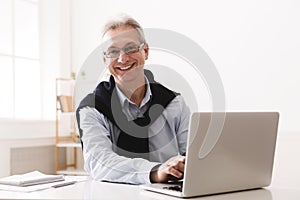 Senior man using computer and looking at camera