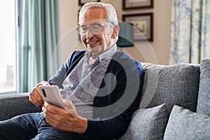 Happy senior man using phone at home