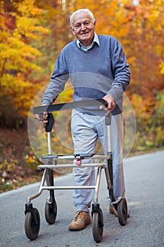 Senior man with a walking disability enjoying a walk in an autumn park