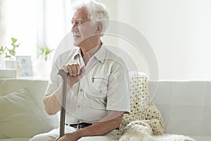 Happy senior man with walking stick relaxing in a nursing house