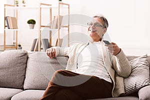 Happy senior man watching tv, sitting on couch