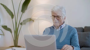 Happy senior man waving hand while having video call at home