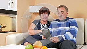 Happy senior man and woman talking on tablet PC at home with the children. Video calling via the internet helps to talk