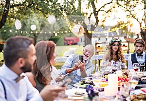 A senior man taking selfie at the wedding reception outside in the backyard.