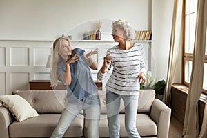 Happy senior mom and adult daughter dancing at home