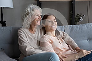 Happy senior mom and adult daughter relax at home