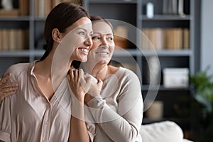 Happy senior mother and adult daughter look in distance dreaming