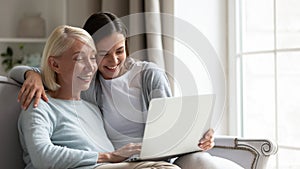 Happy senior mother and adult daughter using laptop together