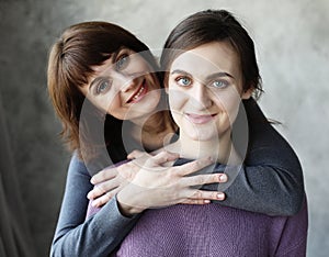 Happy senior mother embracing adult daughter laughing together, older lady hugging young woman