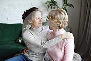 Happy senior mother embracing adult daughter laughing together, smiling excited aged older lady hugging young woman