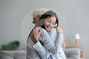 Happy senior mother and grown-up daughter hugging at home
