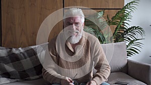 Happy senior old grey haired man with a gray beard talking to webcam make call, smiling mature blogger recording