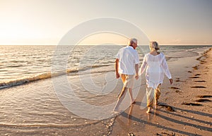 Happy Senior Old Retired Couple Walking Holding Hands on Beach at Sunset