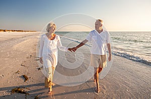 Happy Senior Old Retired Couple Walking Holding Hands on Beach at Sunset