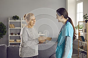 Happy senior patient getting acquainted with a friendly young nurse or physician