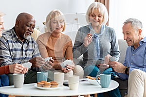 Happy senior people playing cards at nursing home