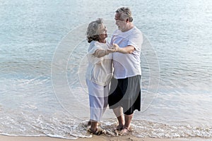 Happy senior retired couple dancing with relax smiling  on sea beach, elder man and woman enjoying with retired vacation.