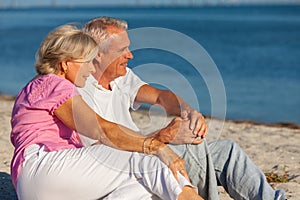 Happy Senior Retired Couple Sitting Smiling on a Beach