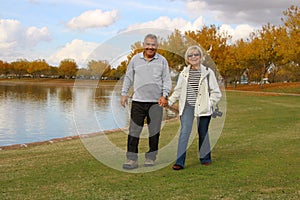 Happy Senior Retired Couple Walking by a Lake at the Park