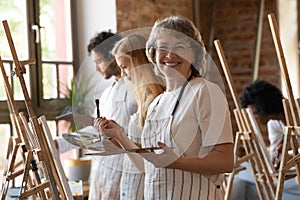 Happy senior retired student of art school drawing in class