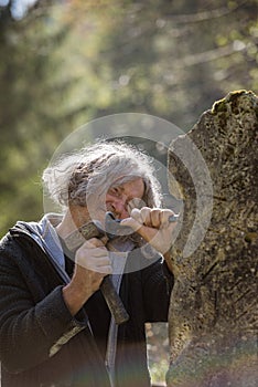 Happy senior sculptor carving in stone