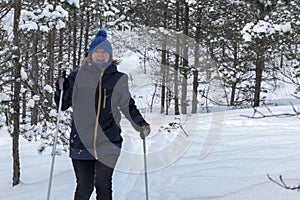 Happy senior skiing in snowy forest hill. Elderly active lifestyle in winter. Senior woman cross country telemark skiing in snowy