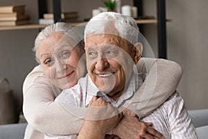 Happy senior wife piggyback pensioner husband smile look at camera