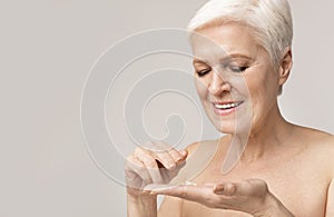 Happy senior woman applying anti-wrinkle cream for skin